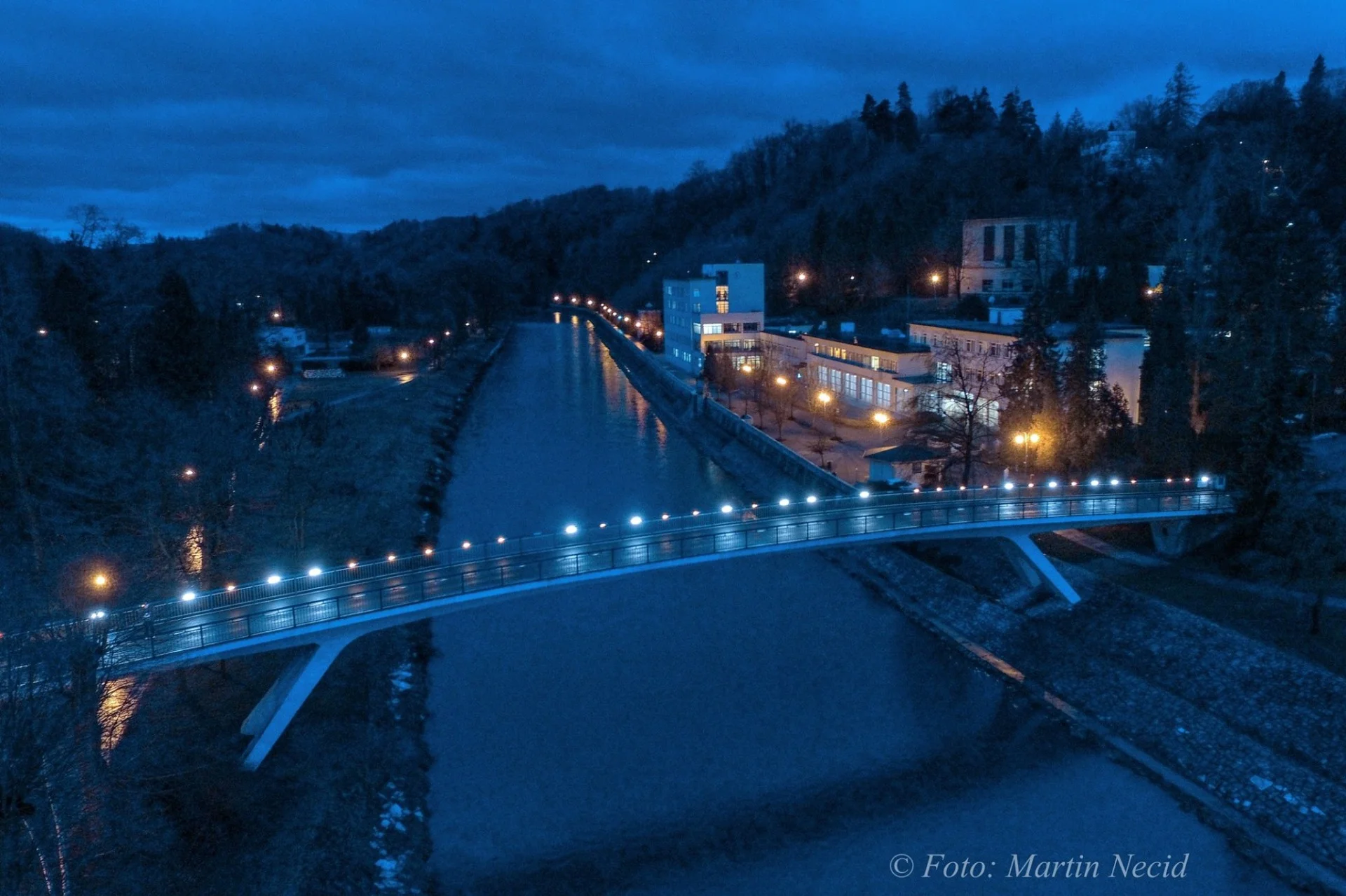Noční pohled na lázně Teplice nad Bečvou s osvětlenými budovami a okolní krajinou.